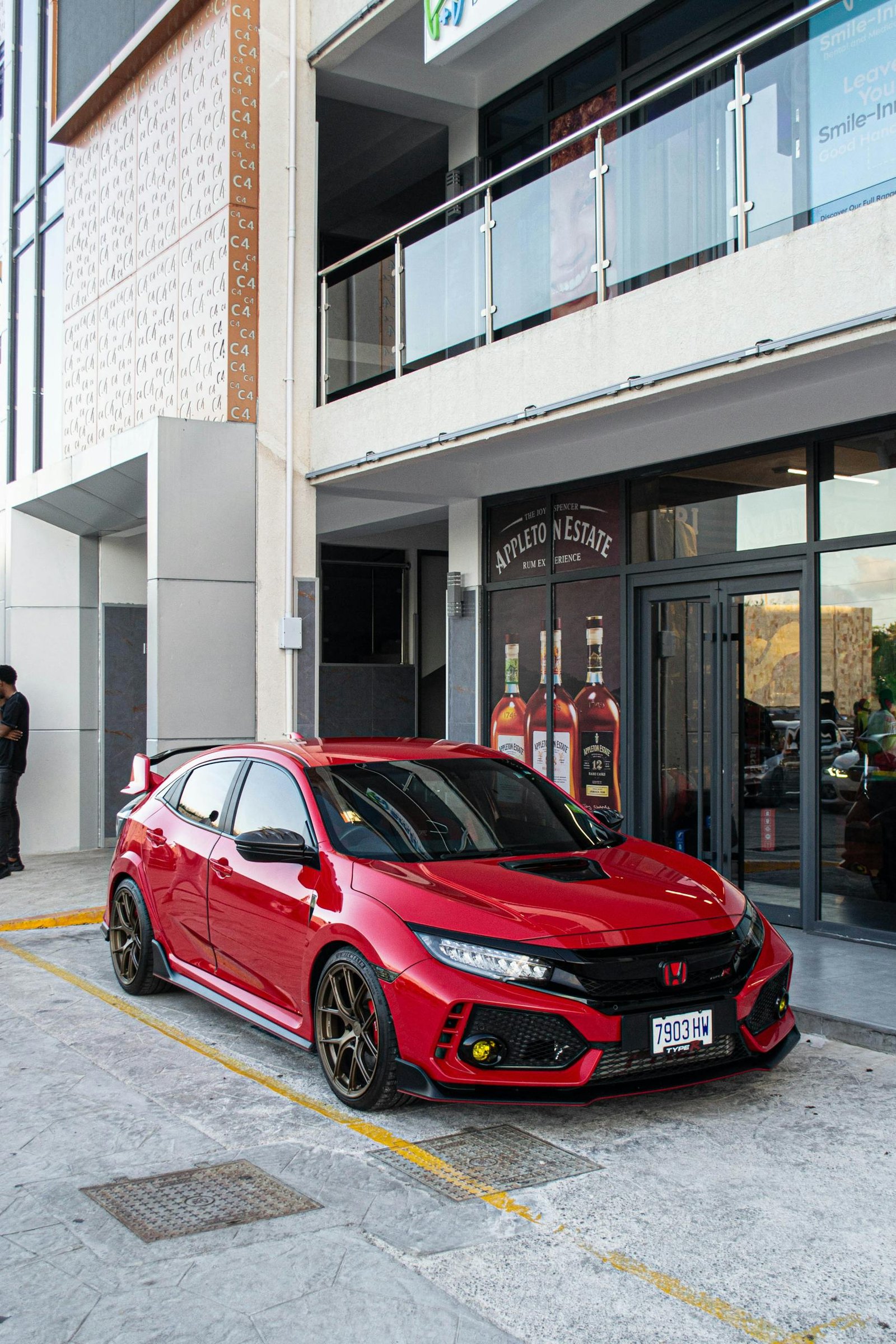 A sleek red hatchback car parked in front of a modern building, enhancing urban street aesthetic.